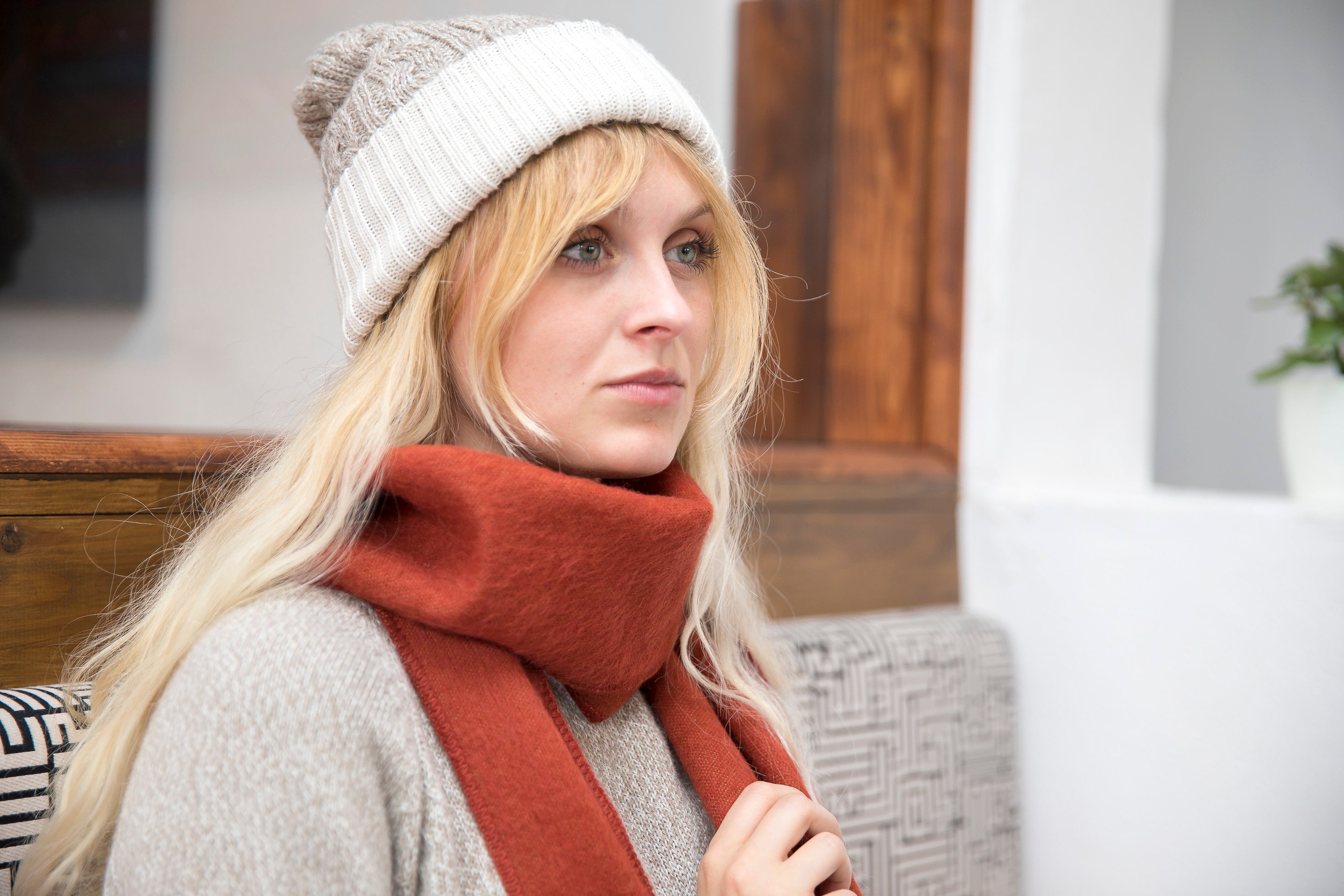 A person wearing a beige reversible hat with a red scarf.