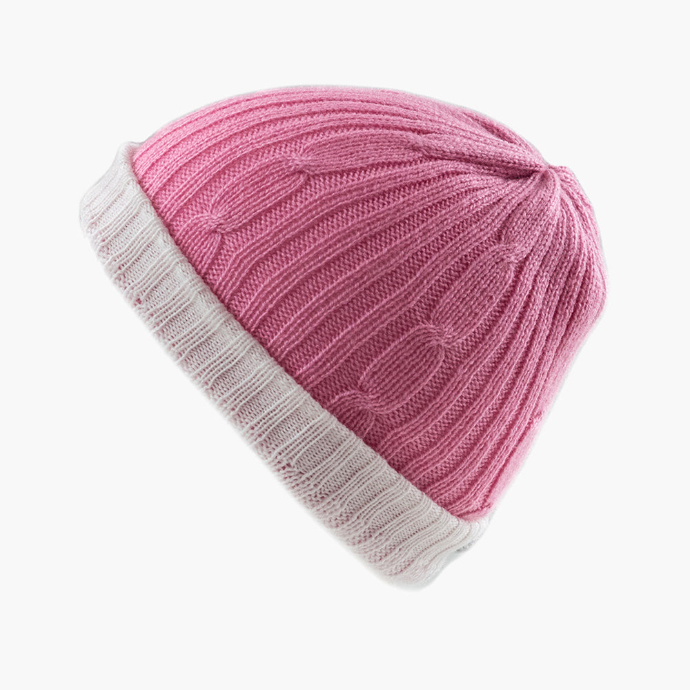 A person wearing a beige reversible hat with a red scarf.